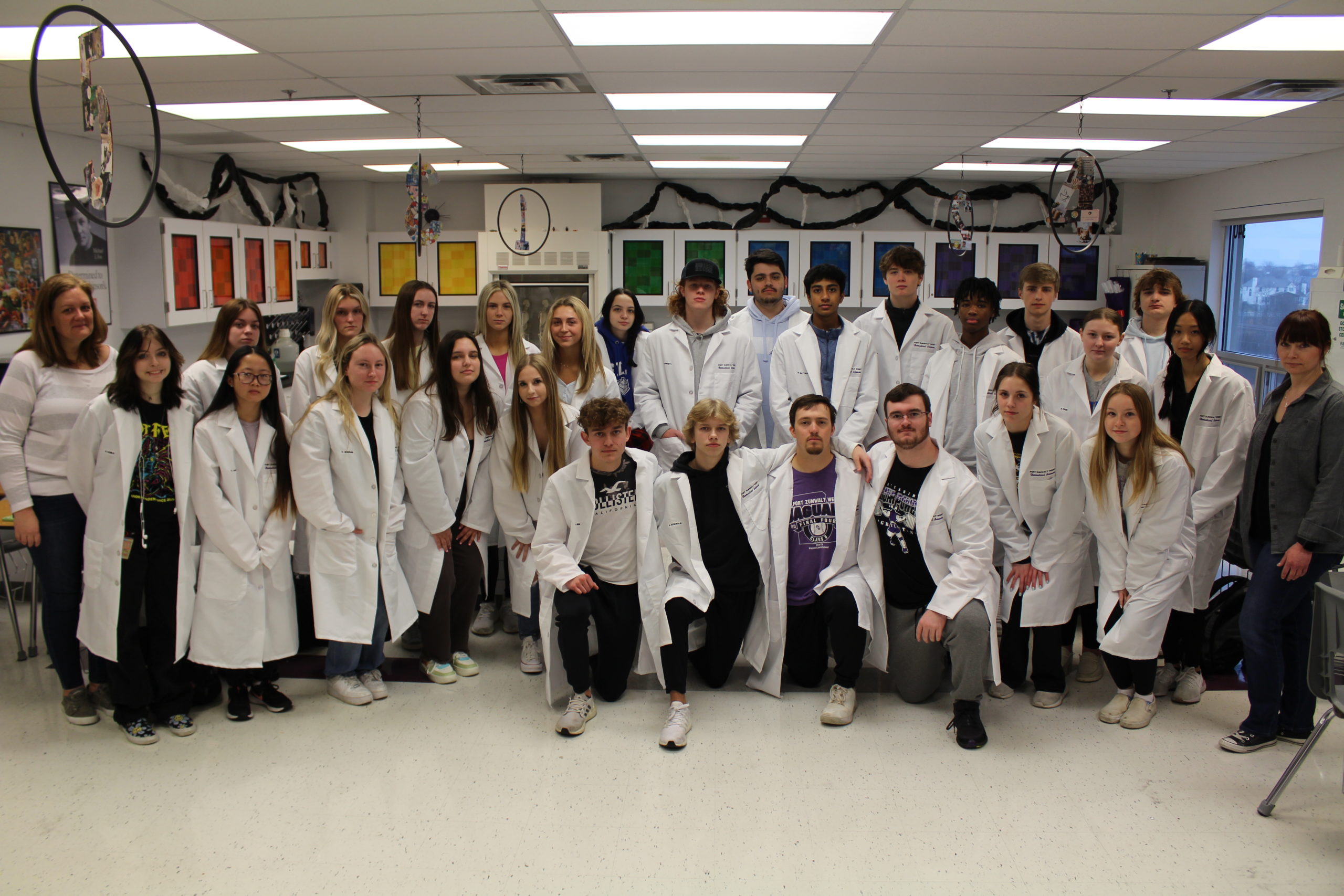 PLTW teachers, Marie Jackson and Justina Davitz pose for a photo with the seniors that received white coats.